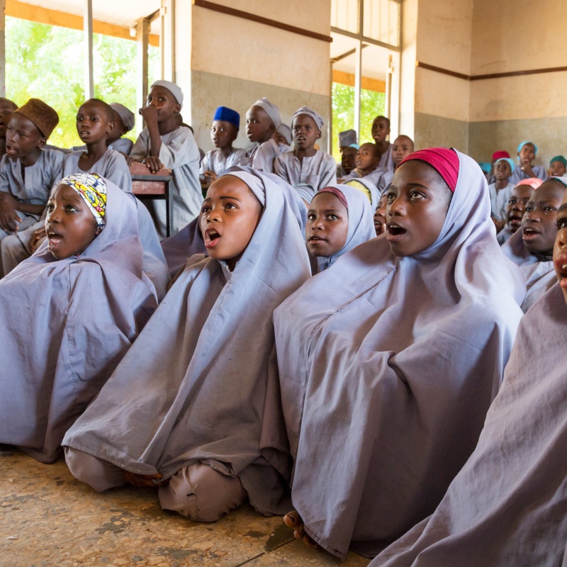 Sumayya Ado, 13 (second from right), and other girls sit on the floor at Janbulo Islamiyya Primary School, Roni, Jigawa State, Nigeria.  Asked if she could change one thing about the school, she says, “I would add more classrooms. Our classes are too congested.” Credit: GPE/Kelley Lynch